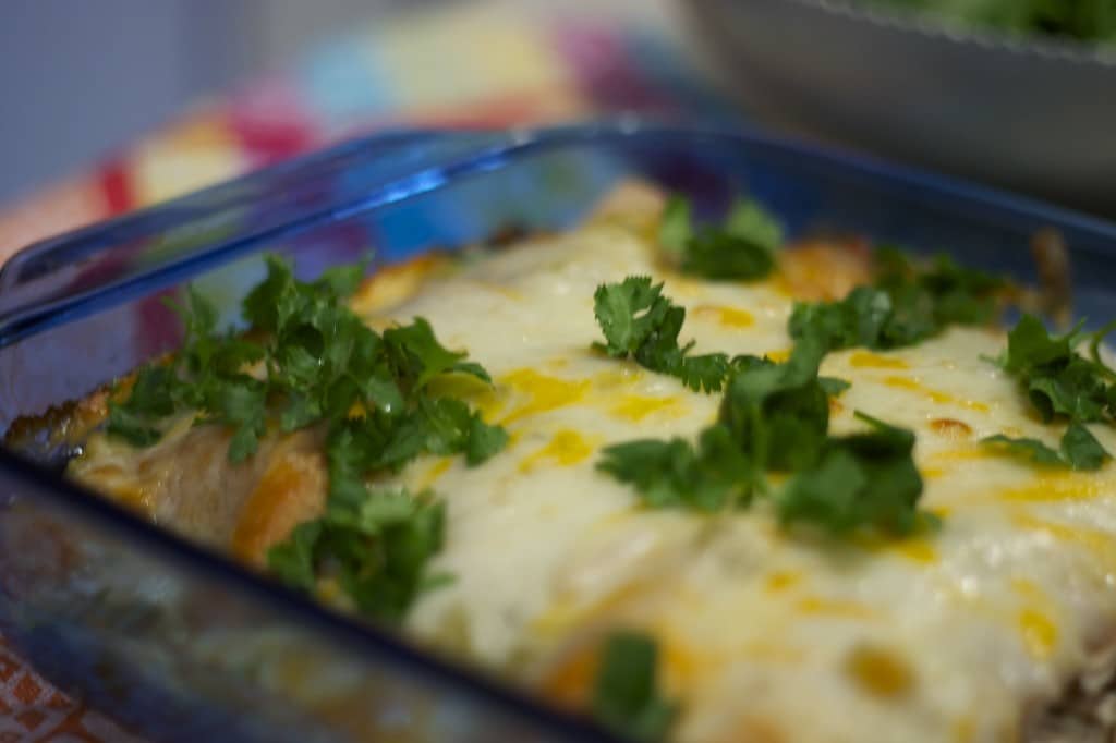 White chicken enchiladas in a blue glass baking pan.