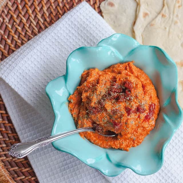 Red pepper hummus in a blue flower bowl.