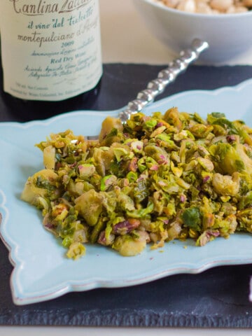 side view of cooked shaved brussel sprouts on light blue dish with spoon