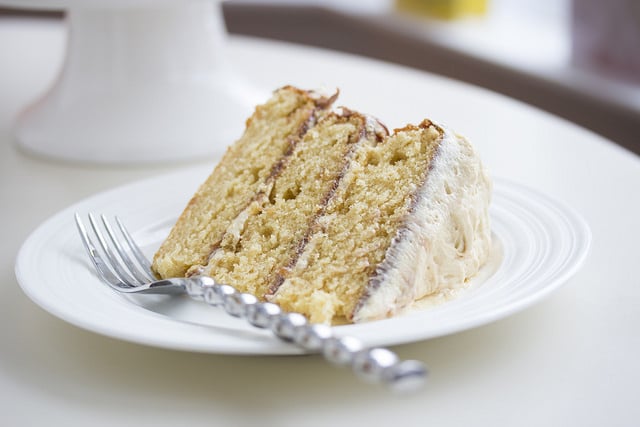 A slice of peanut butter cake on white plate with silver fork 