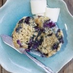 top view of blueberry muffins with pat of butter on blue plate