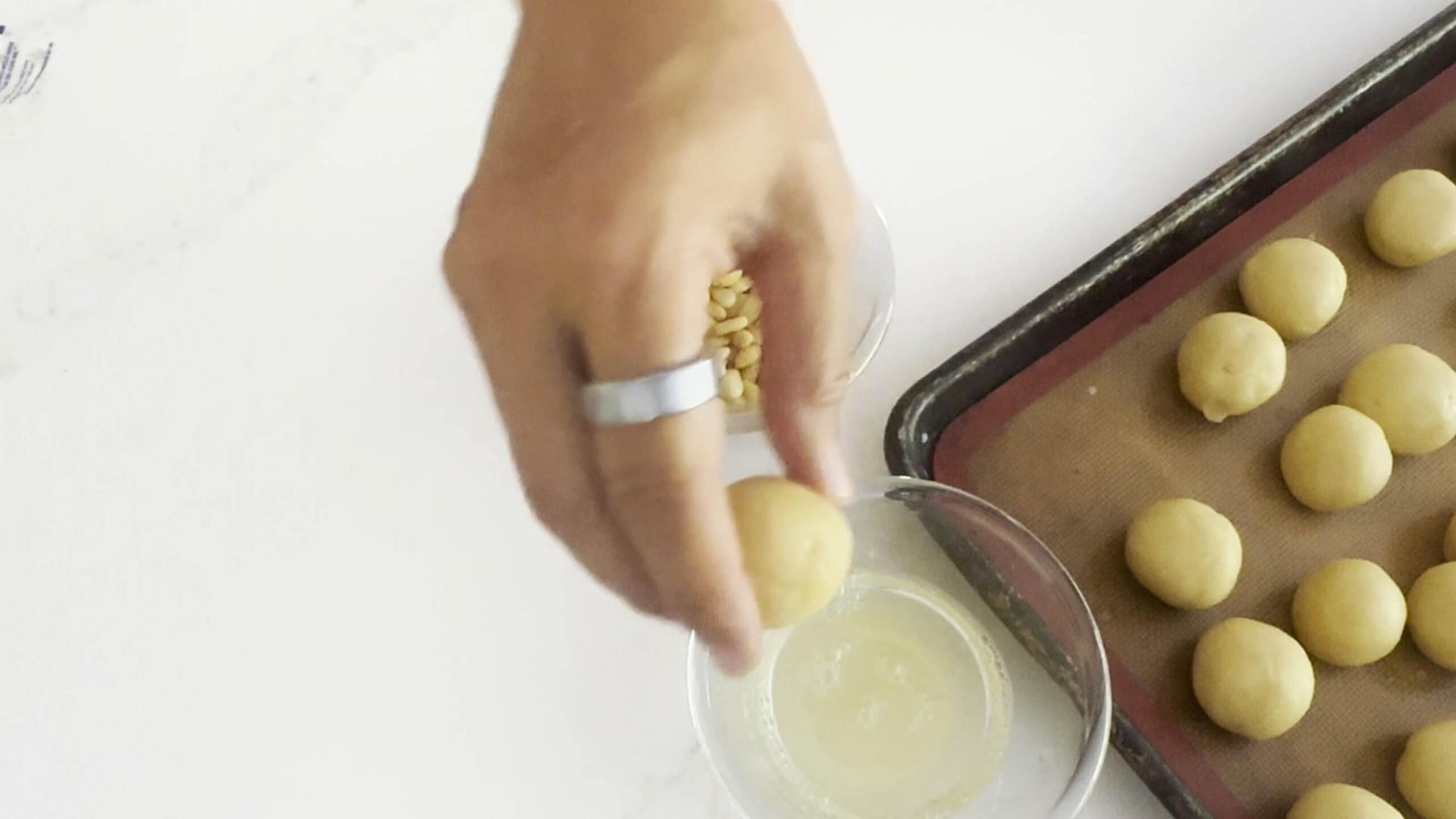 Dipping cookie balls into egg white wash. 
