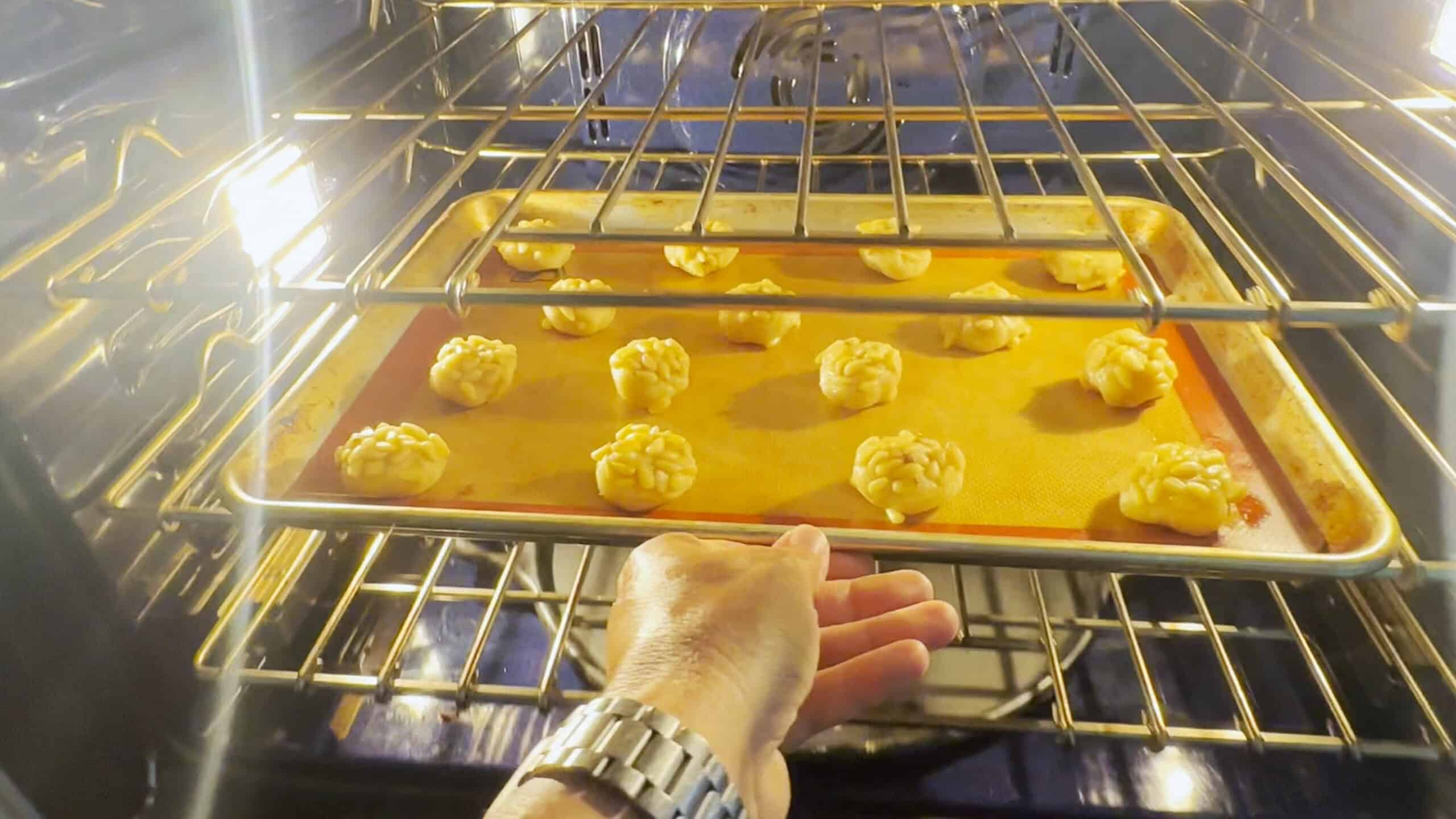 Cookies on a tray; they are slightly flattened and in the oven to be baked. 