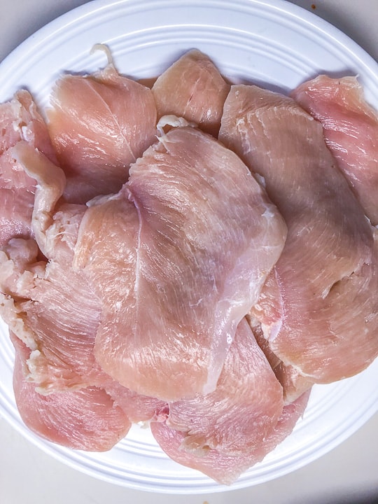 plate of raw chicken breast sliced thin