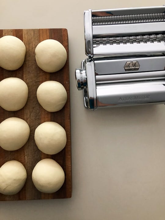 balls of dough resting near pasta rolling machine
