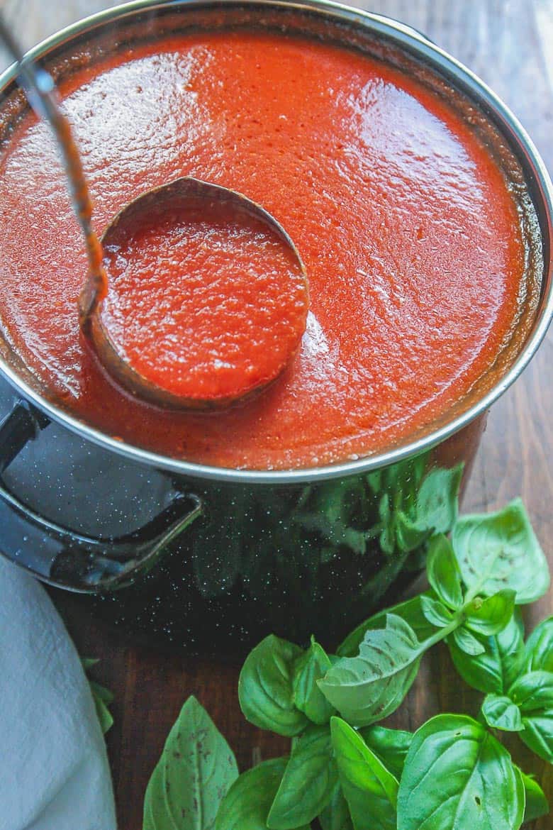 pot of homemade spaghetti sauce with a ladle scooping out sauce.