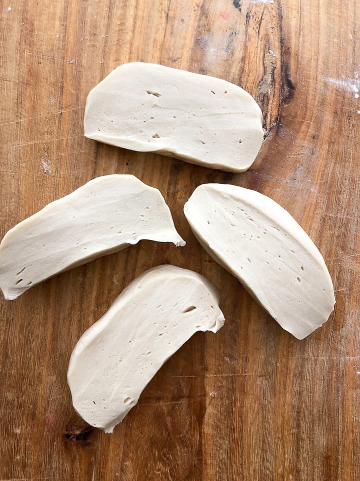 Slices of dough ready to be flattened on wooden board. 