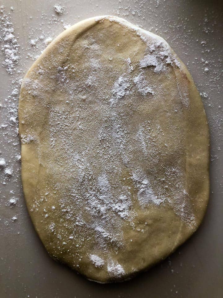 Flour sprinkled on flattened dough. 