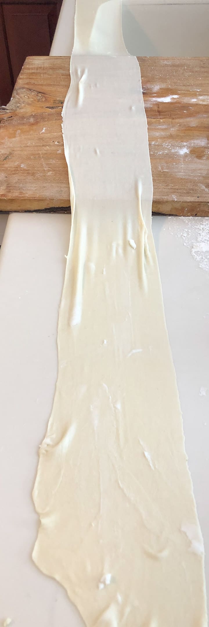 A very long and very thin strip of dough after passing through pasta machine. 