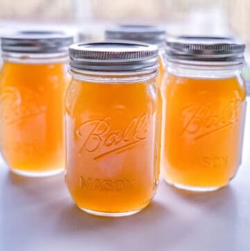 front view of pint sized glass jars filled with fresh chicken stock