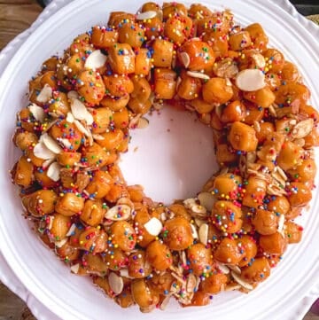 overhead view of struffoli arranged like a wreath on white dinner plate