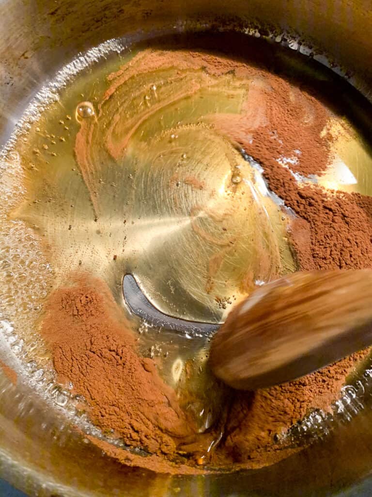 overhead view of warming honey with cinnamon in saute pan for struffoli