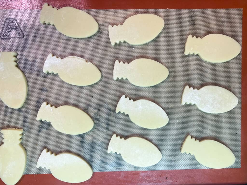 half baking sheet with raw cookies shaped like christmas bulbs