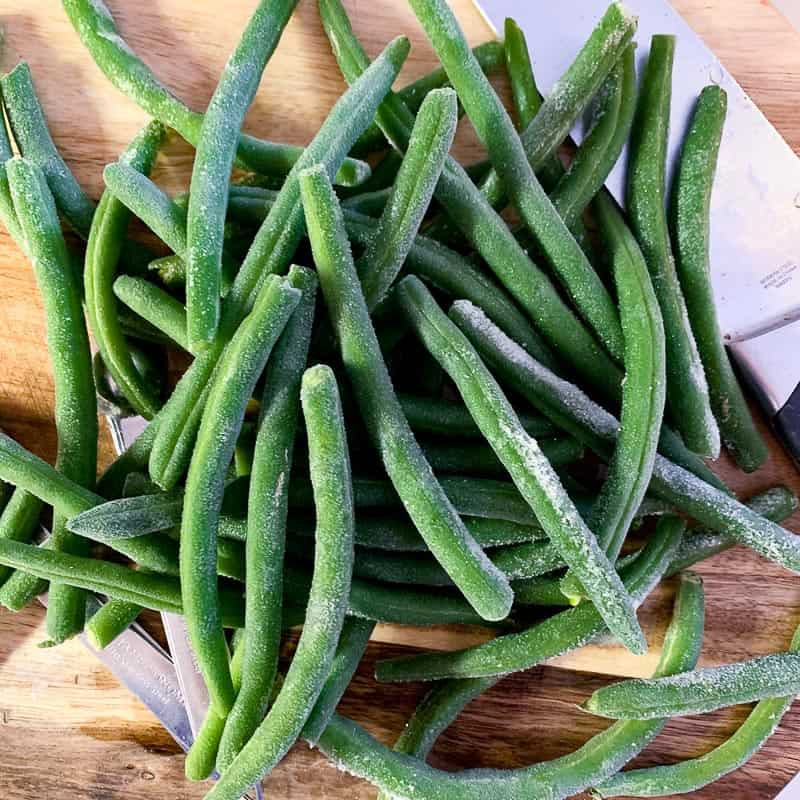 frozen fresh green beans on cutting board ready to be sliced