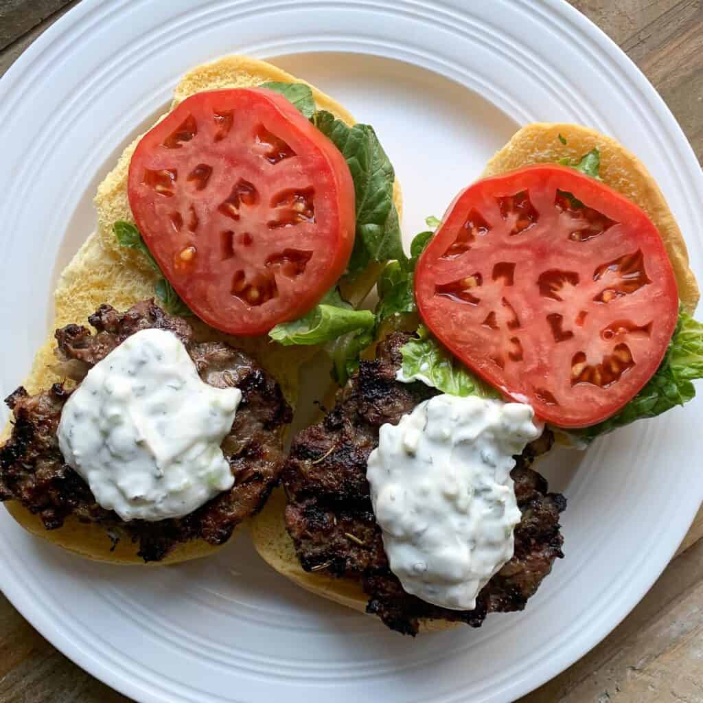 overhead view of open face gyro burgers on bun with tomato lettuce and tzatziki sauce