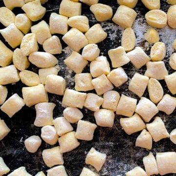 close up view of raw ricotta gnocchi on black metal tray