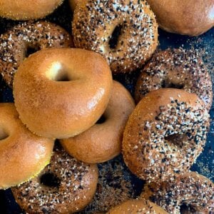 top view of NY style bagels with and without everything topping on black sheet pan