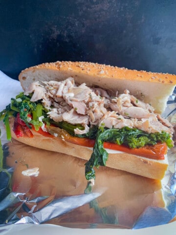 side view of philly roast pork sandwich with brocoli rabe and roasted peppers
