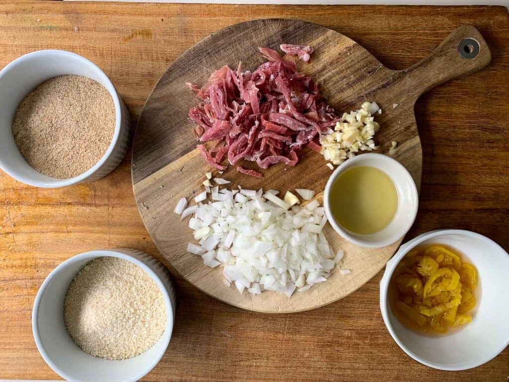 Ingredients for flavoring escarole are shown in bowls on wooden board