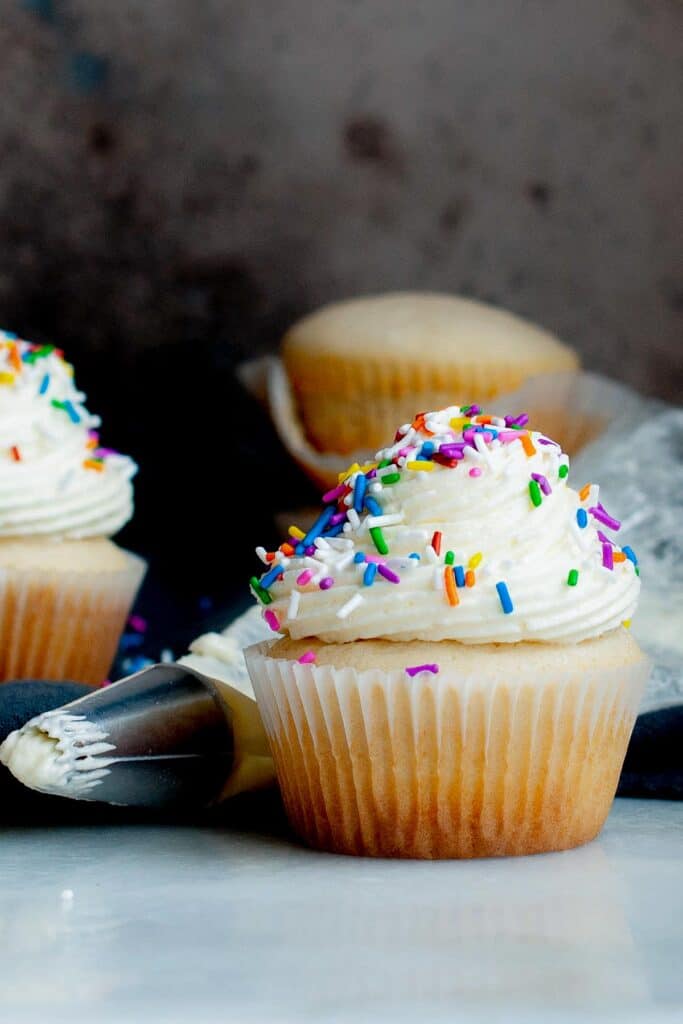 side view of vanilla cupcake with buttercream frosting and colored sprinkles