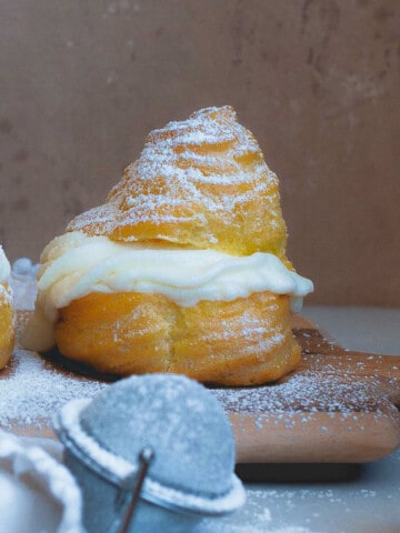 side view of a single cream puff with powdered sugar