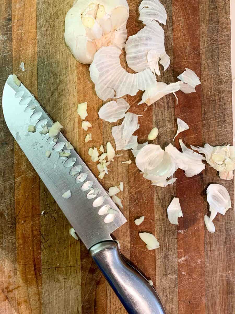 chopped garlic with knife on cutting board