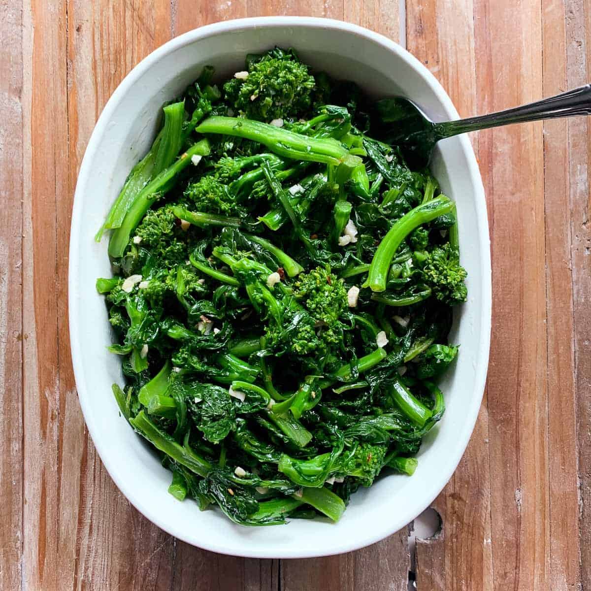 overhead view of cooked broccoli rabe in white casserole dish on wooden background Broccoli rabe is a great change of pace for your weeknight veggie rotation. And with just a handful of ingredients, it's a breeze to make!