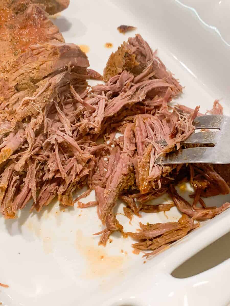 close up view of beef being shredded with large fork