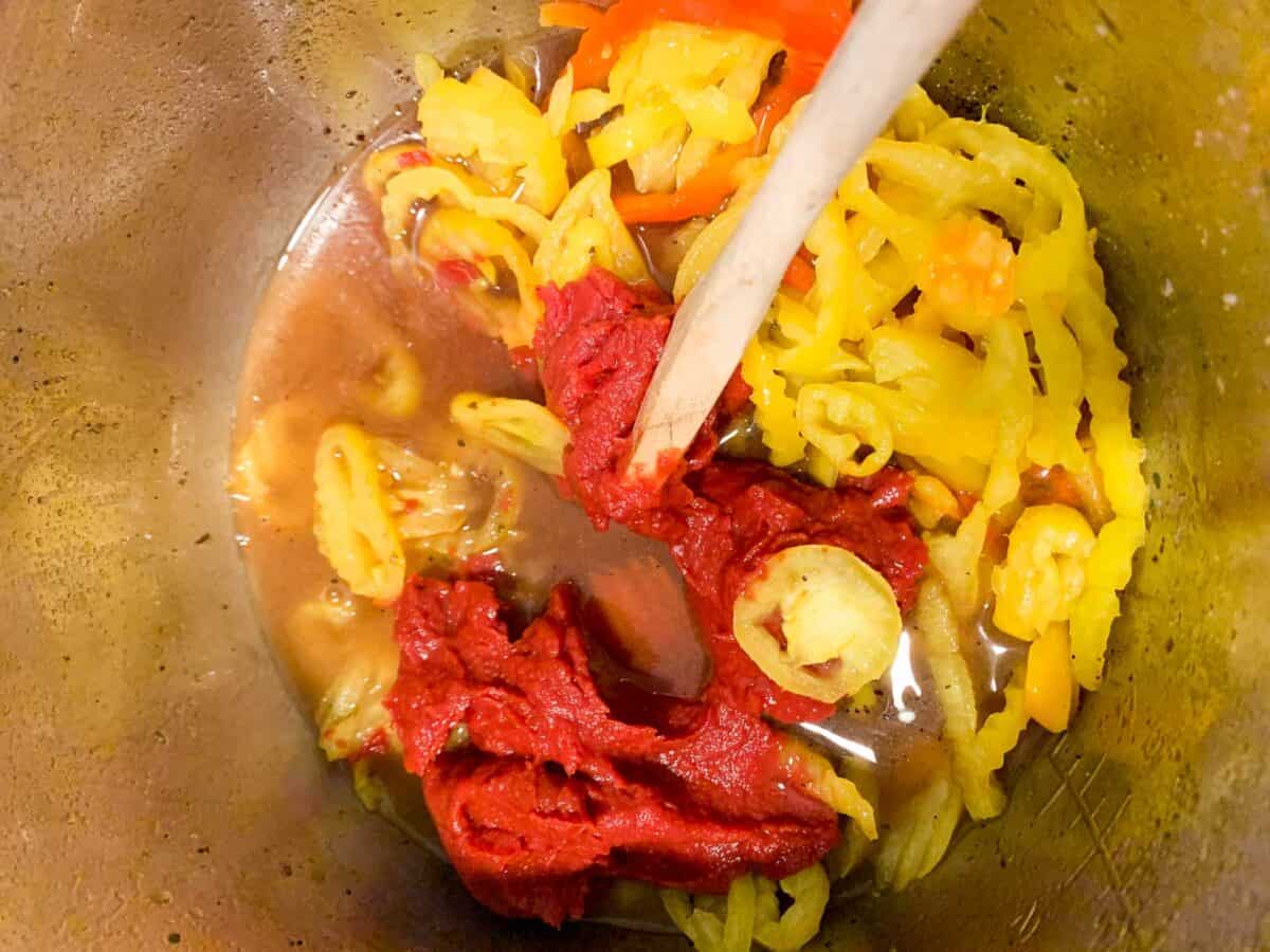 peppers and tomato paste in pot with wooden spoon