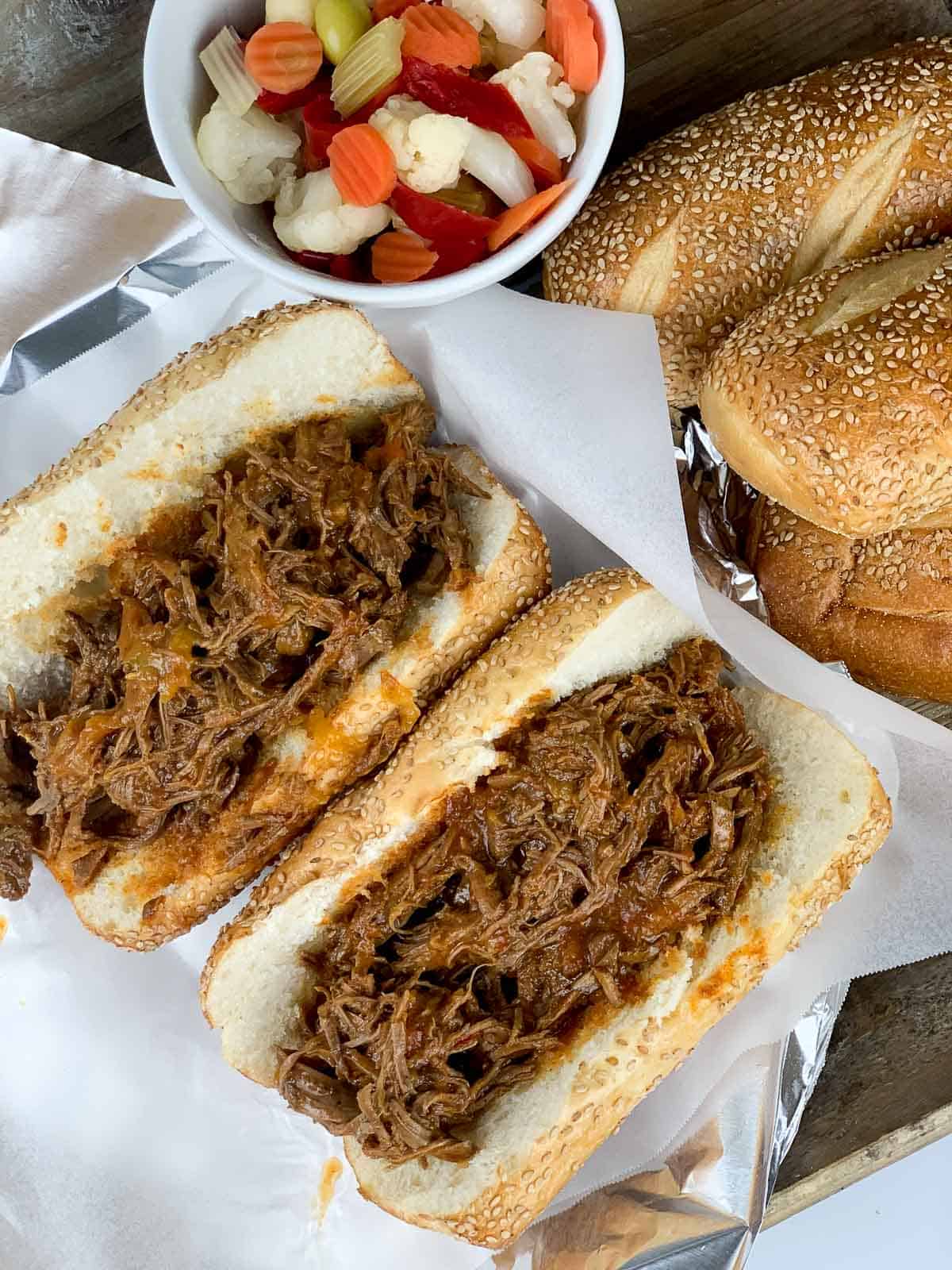 overhead view of italian beef on seeded rolls with pickled giardiniera