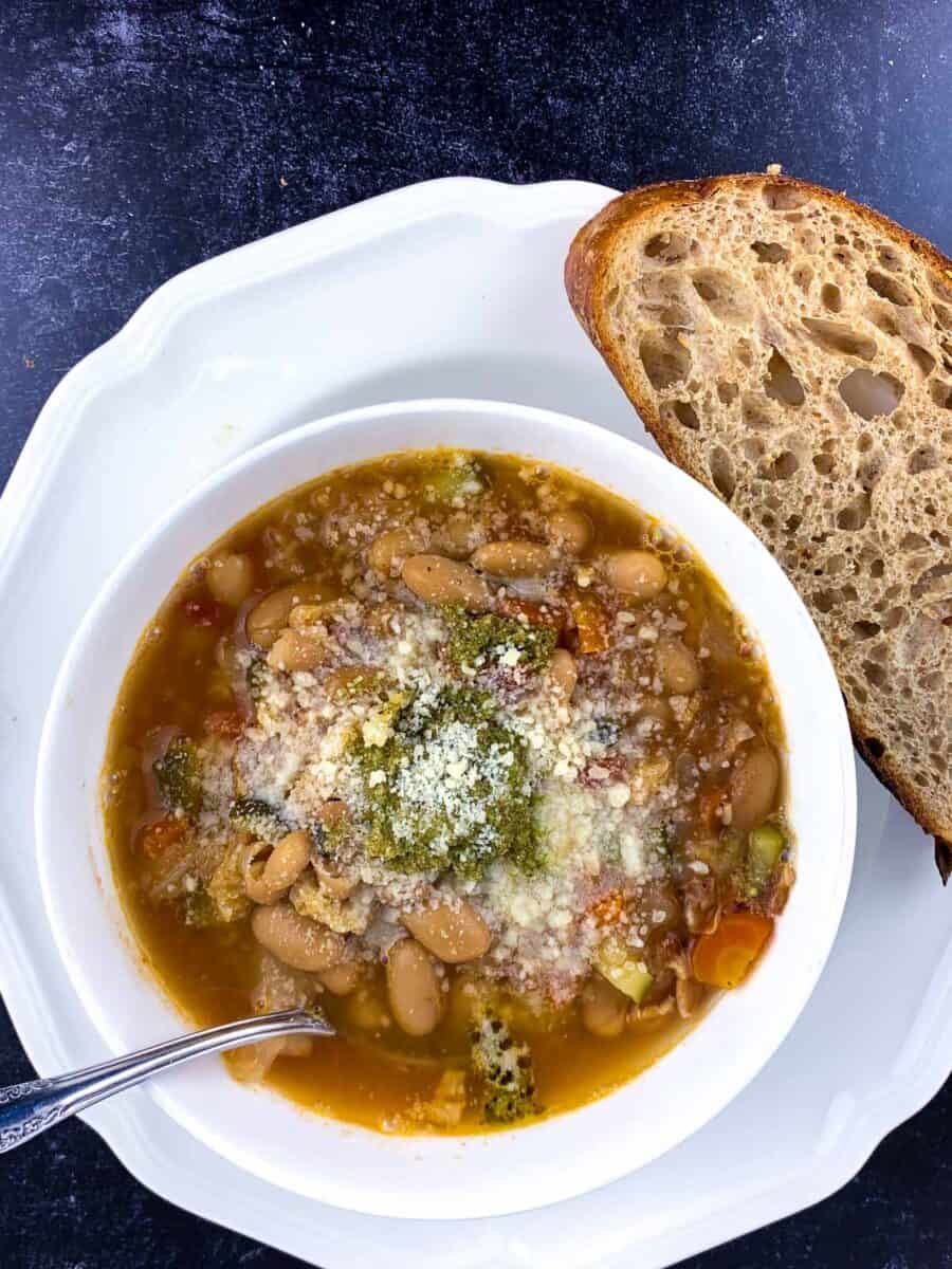 top view of minestrone soup in white bowl with silver spoon on black table How To Make the Best Homemade Minestrone