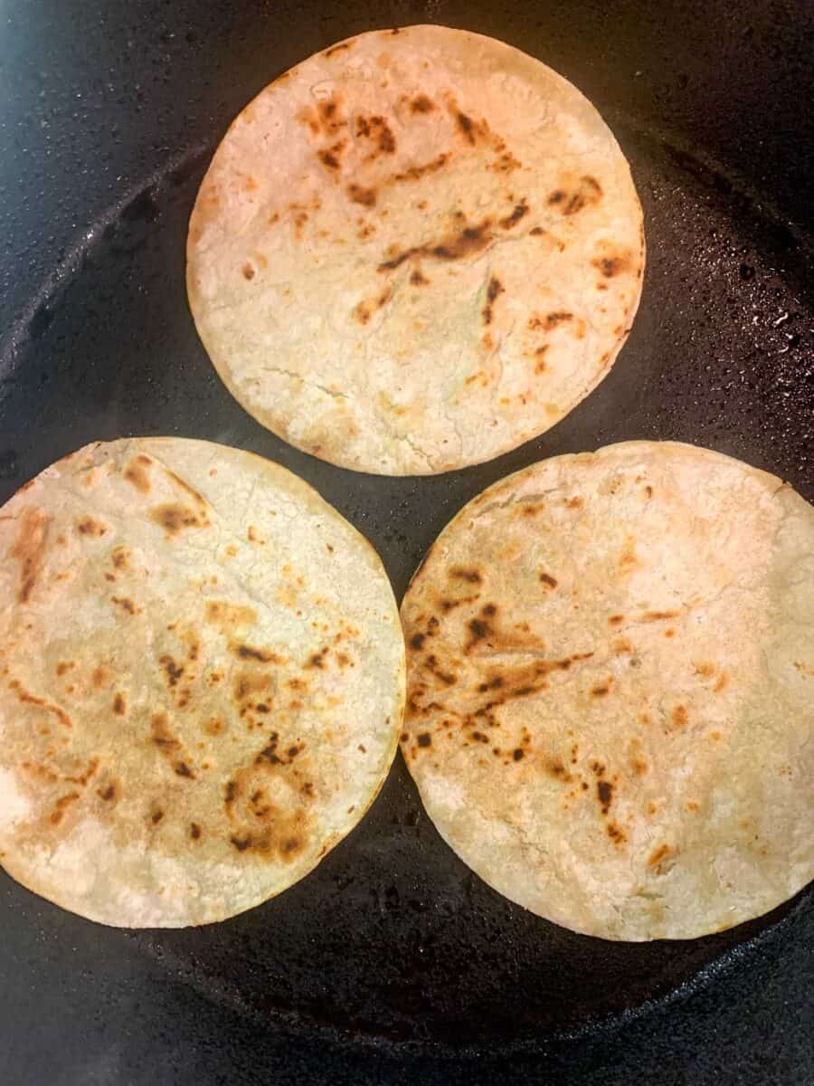 three corn tortillas in pan after toasting