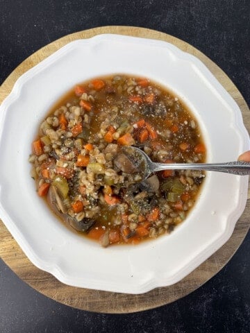 top view of mushroom barley soup in white bowl with spoon
