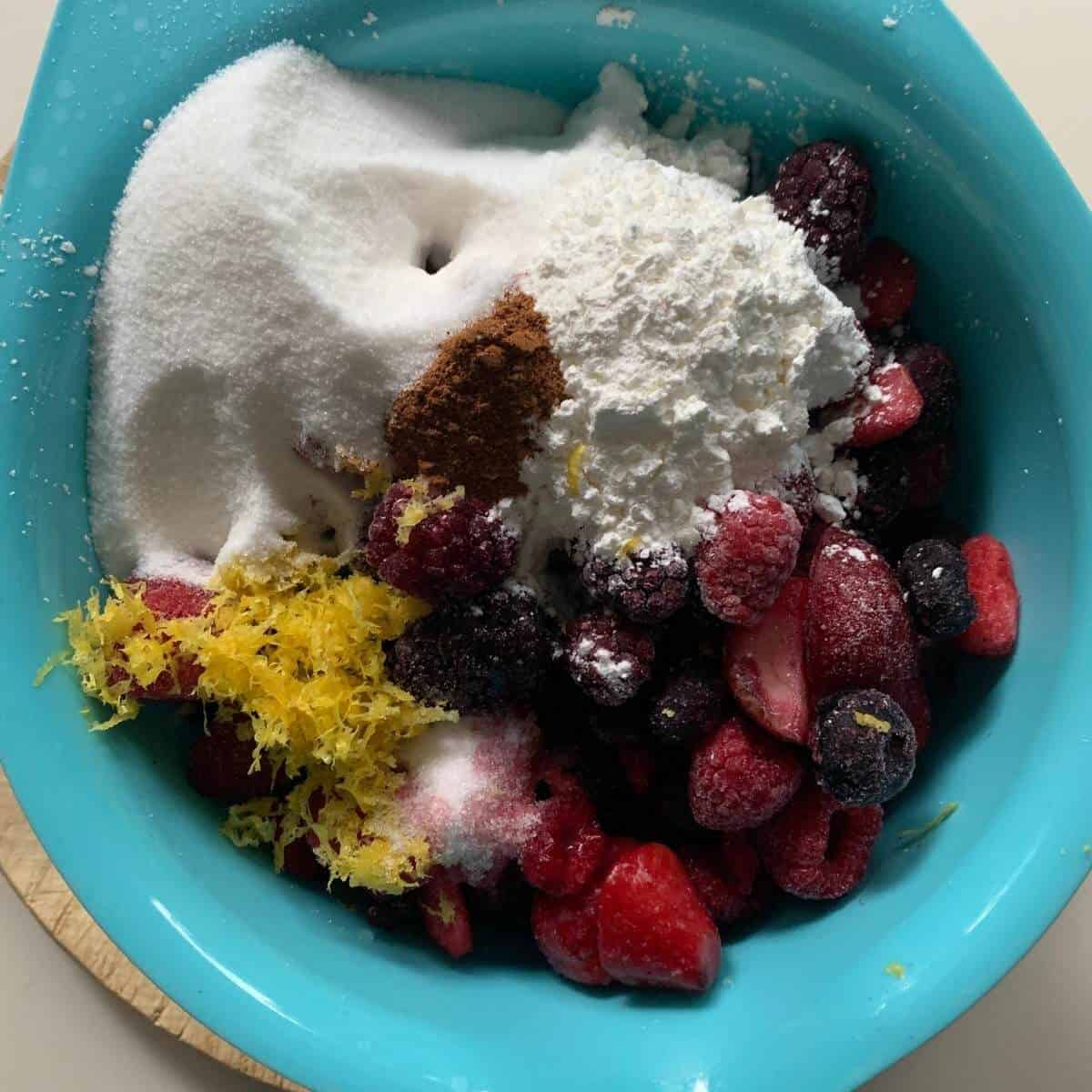 mixed berry pie filling ingredients in blue bowl