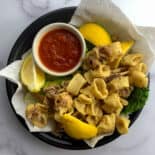 fried calamari with lemon and marinara sauce on plate