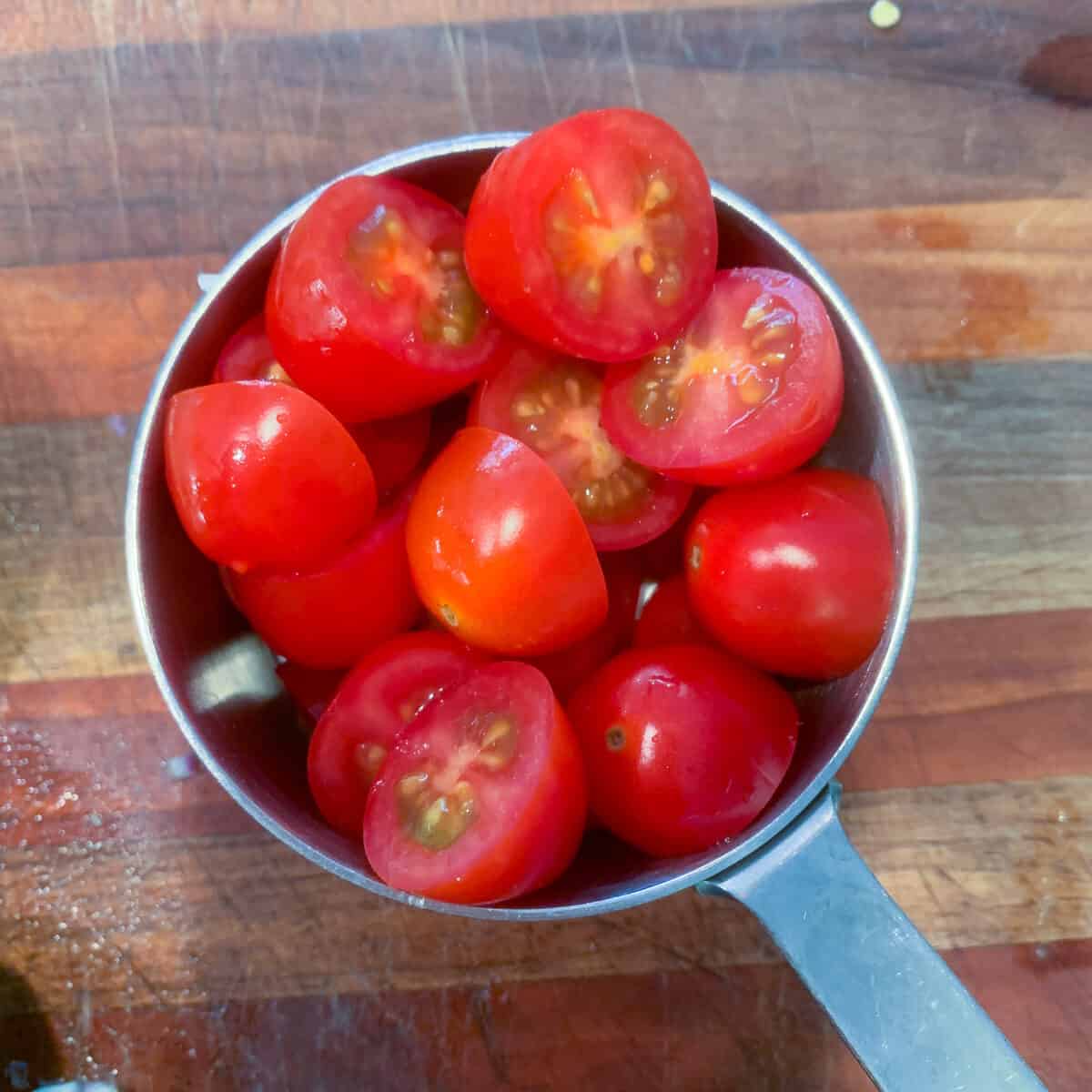 sliced grape tomatoes in measuring cup