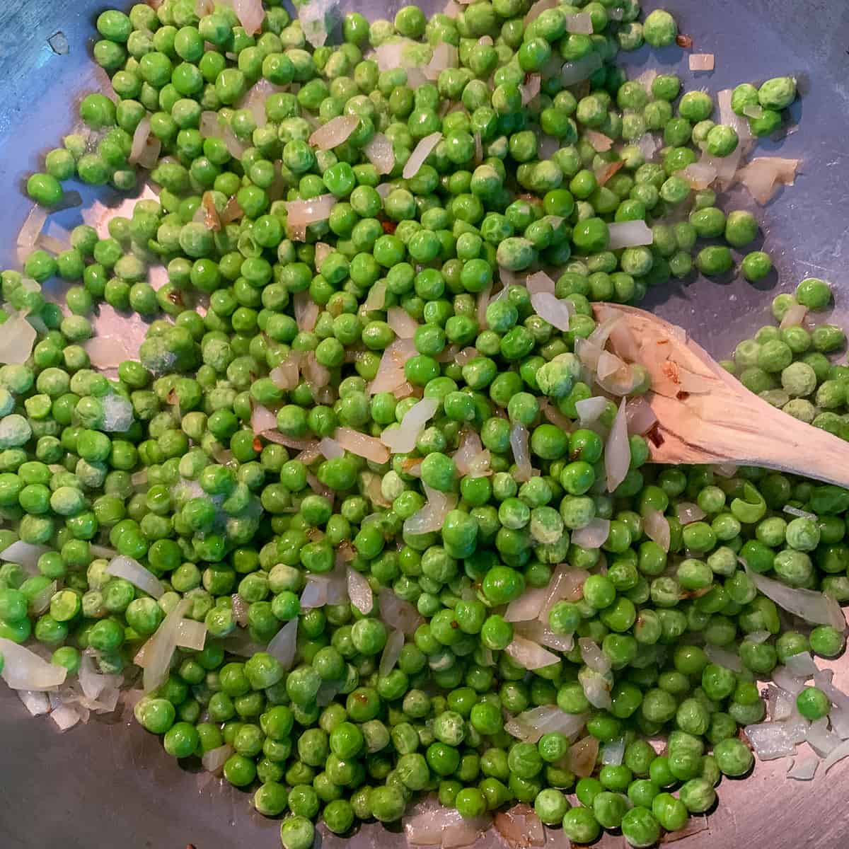 close up view of peas with onions cooking for one pot pasta with peas