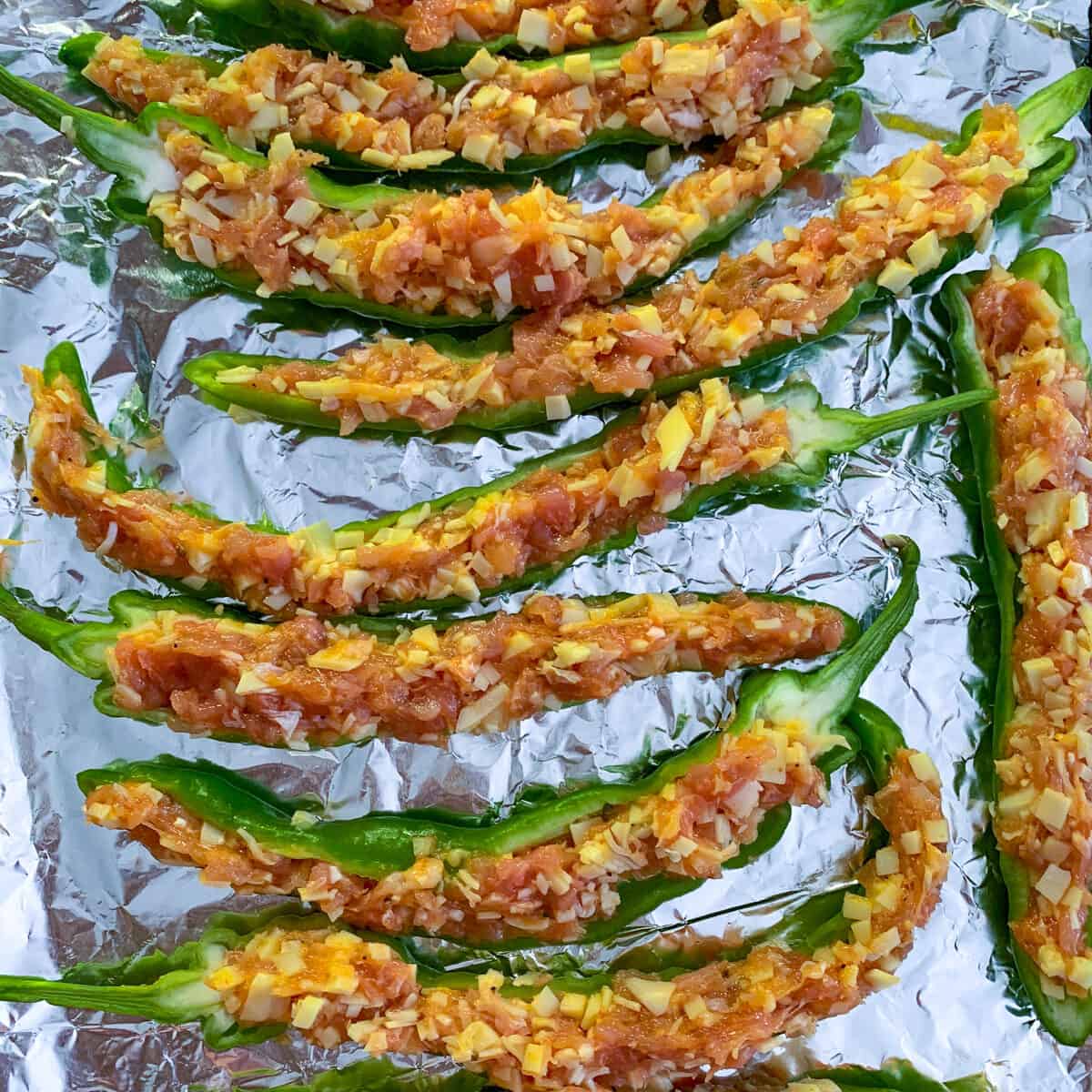 stuffed Italian long hots on aluminum foil ready to be topped with breadcrumbs and baked