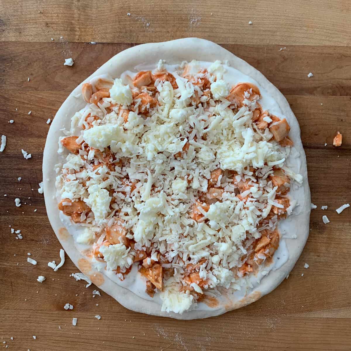 unbaked buffalo chicken pizza on wooden background