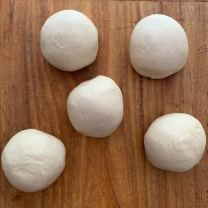 5 balls of dough on wooden board