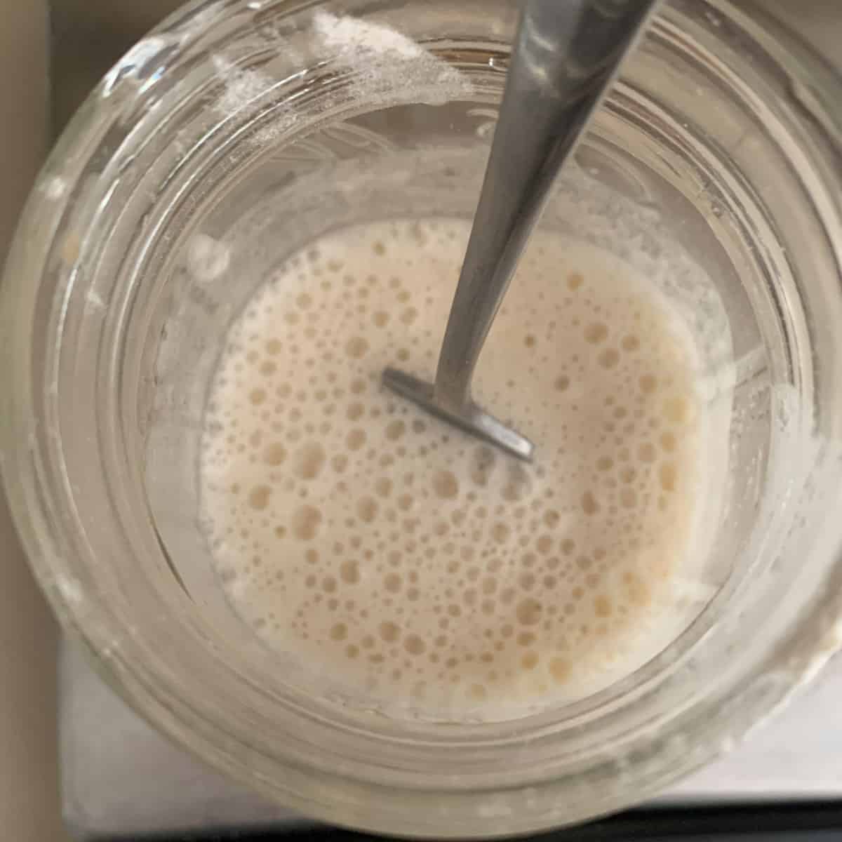 top view of uncooked tangzhong ingredients just mixed in small glass jar with fork.