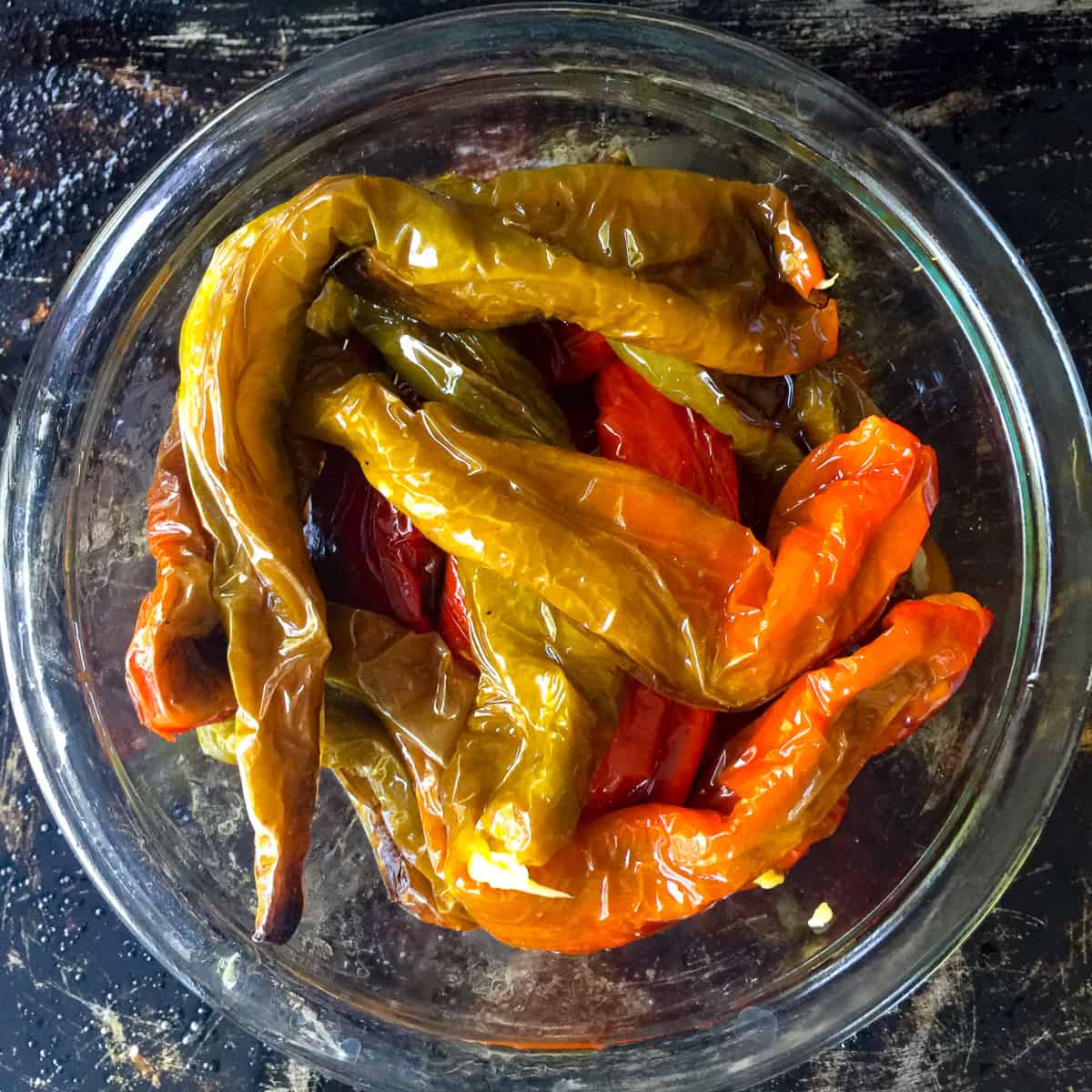 glass bowl with red and green Italian long hot peppers on baking sheet