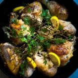 top view of cooked Mediterranean (Italian) skillet roasted chicken with fresh herbs and lemon