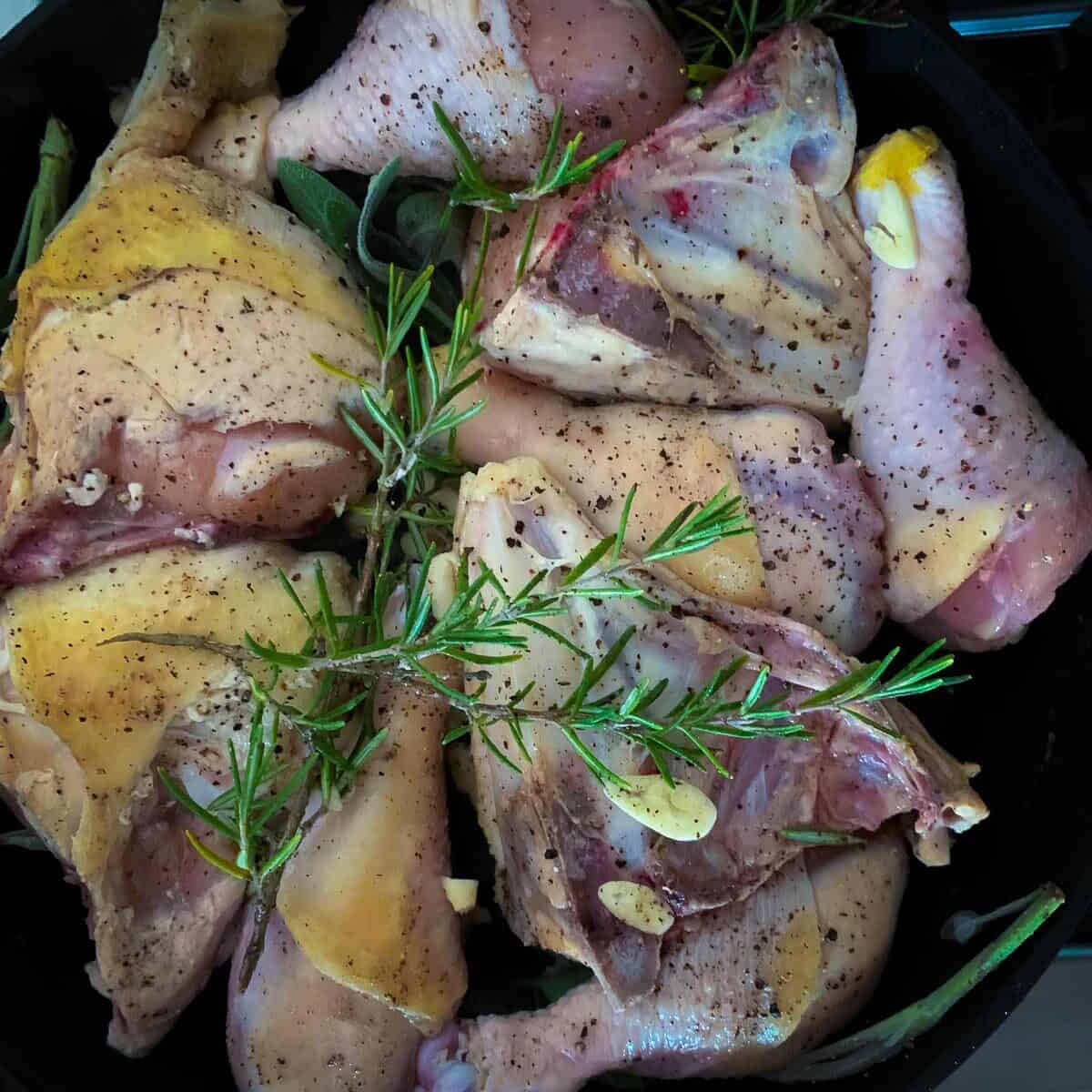 close up view of chicken cooking on stovetop in black skillet