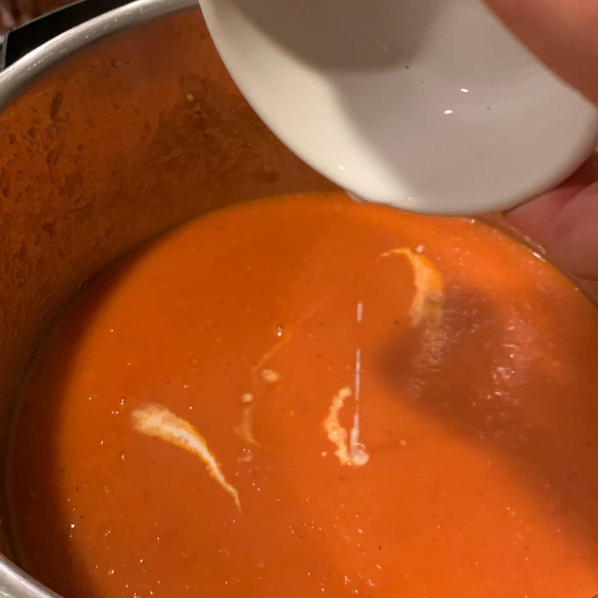 pouring milk into finish tomato soup
