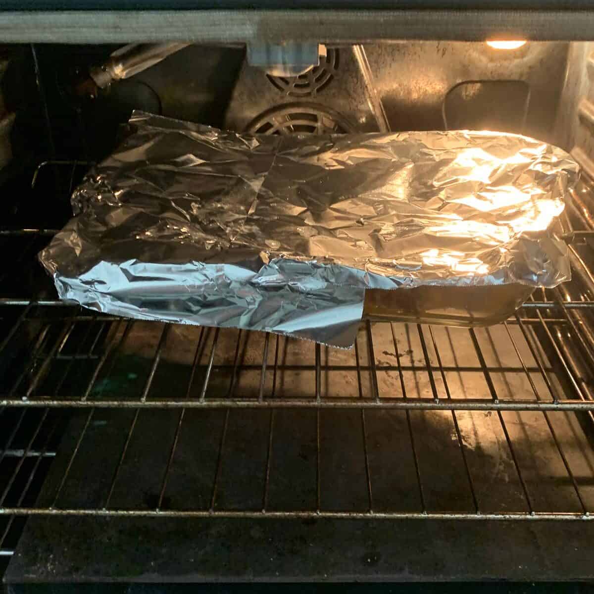 tin foiled covered pan of stuffed peppers in oven
