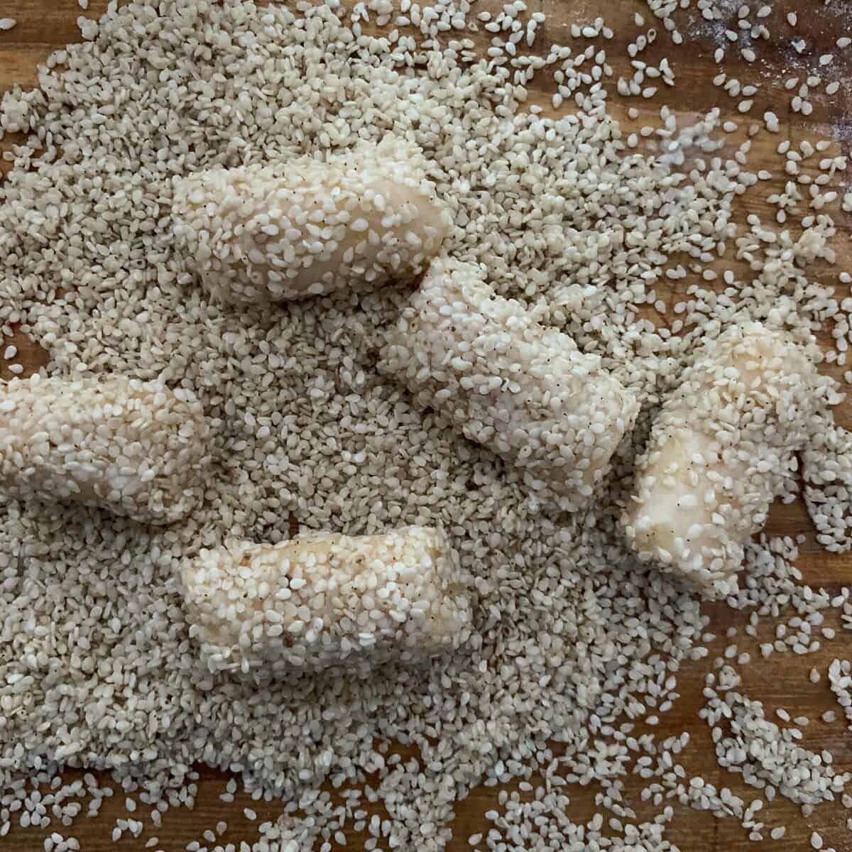 rolling cookies in sesame seeds