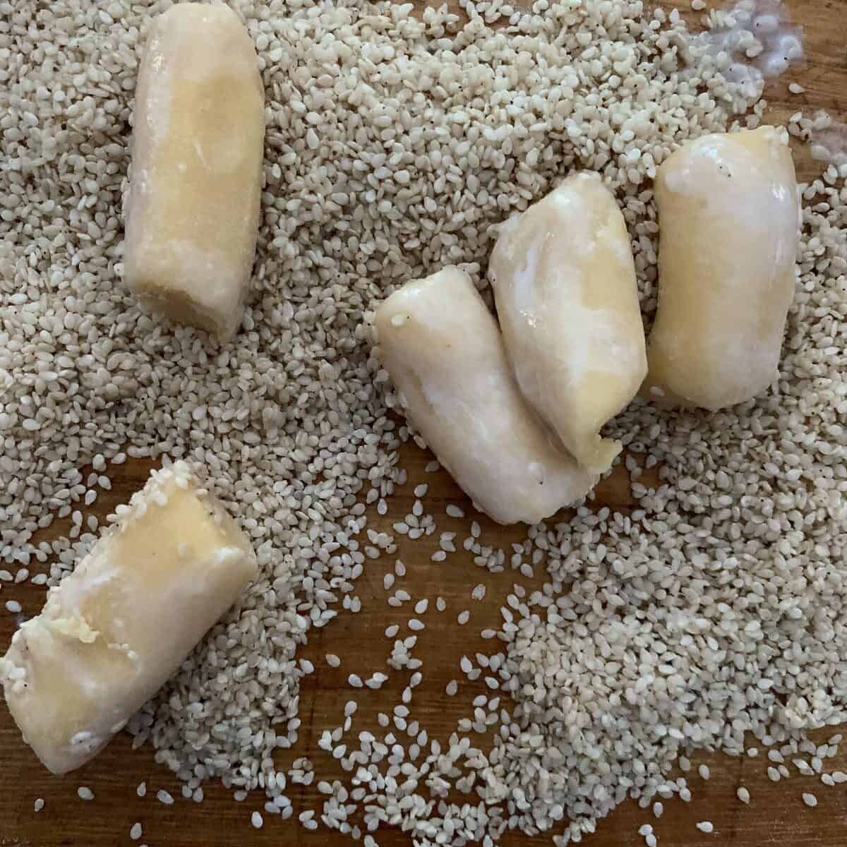 unbaked cookies brushed with milk about to roll in sesame seeds