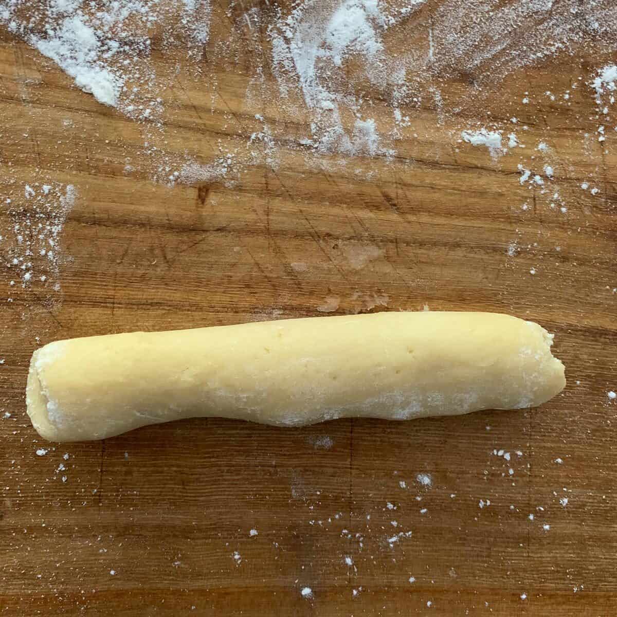 log of cookie dough on wooden board