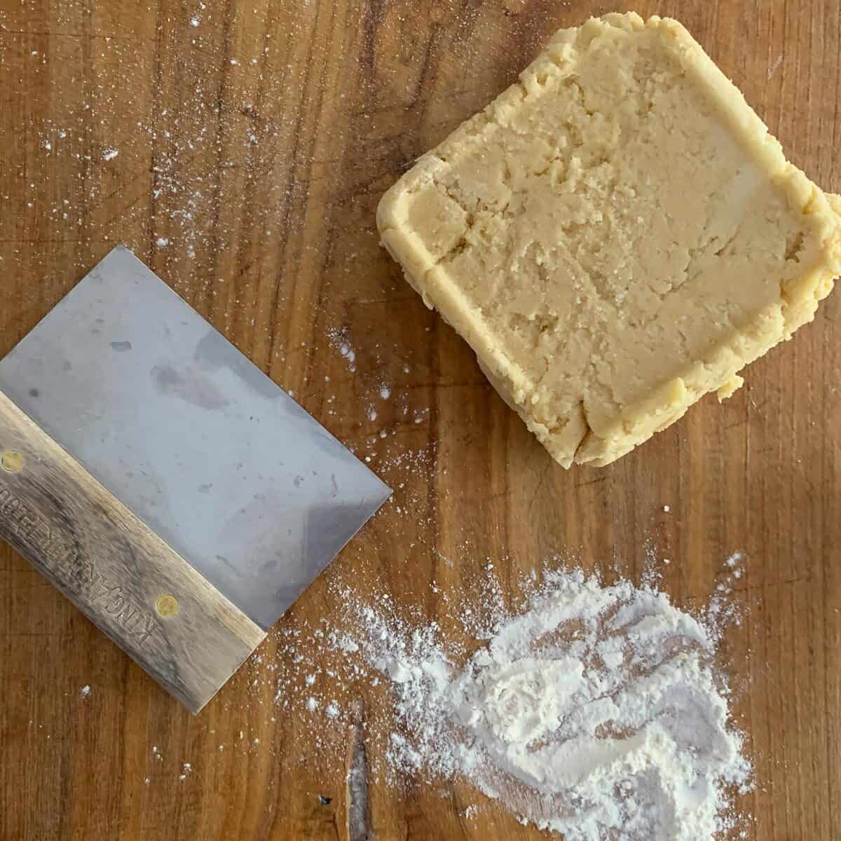 cookie dough after refrigerating on wooden board with flour and bench knife